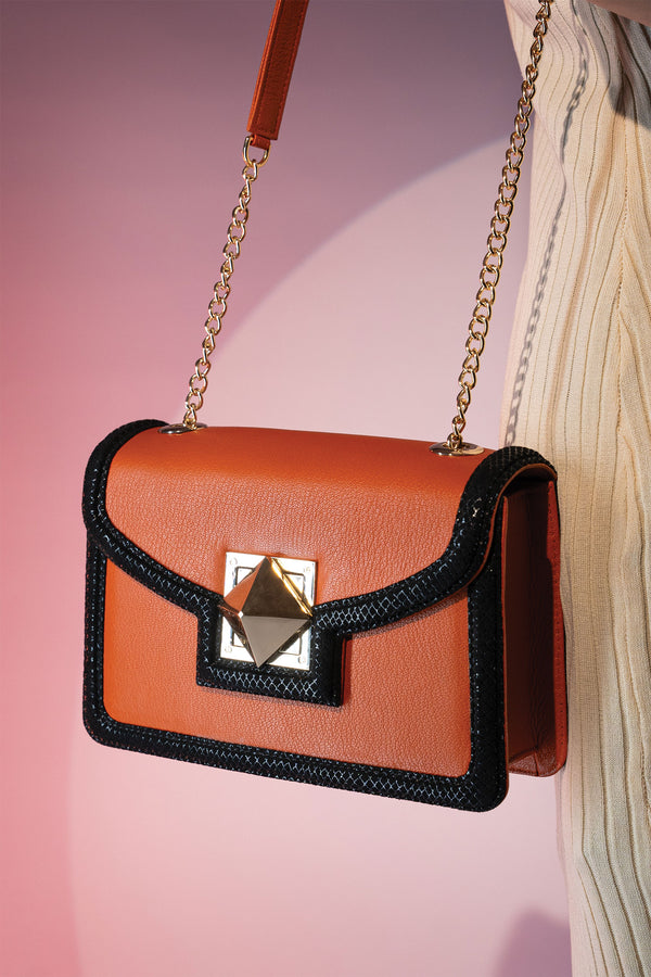 Women's leather shoulder bag in orange colour and black binding with gold twist lock and retractable gold chain strap by JULKE